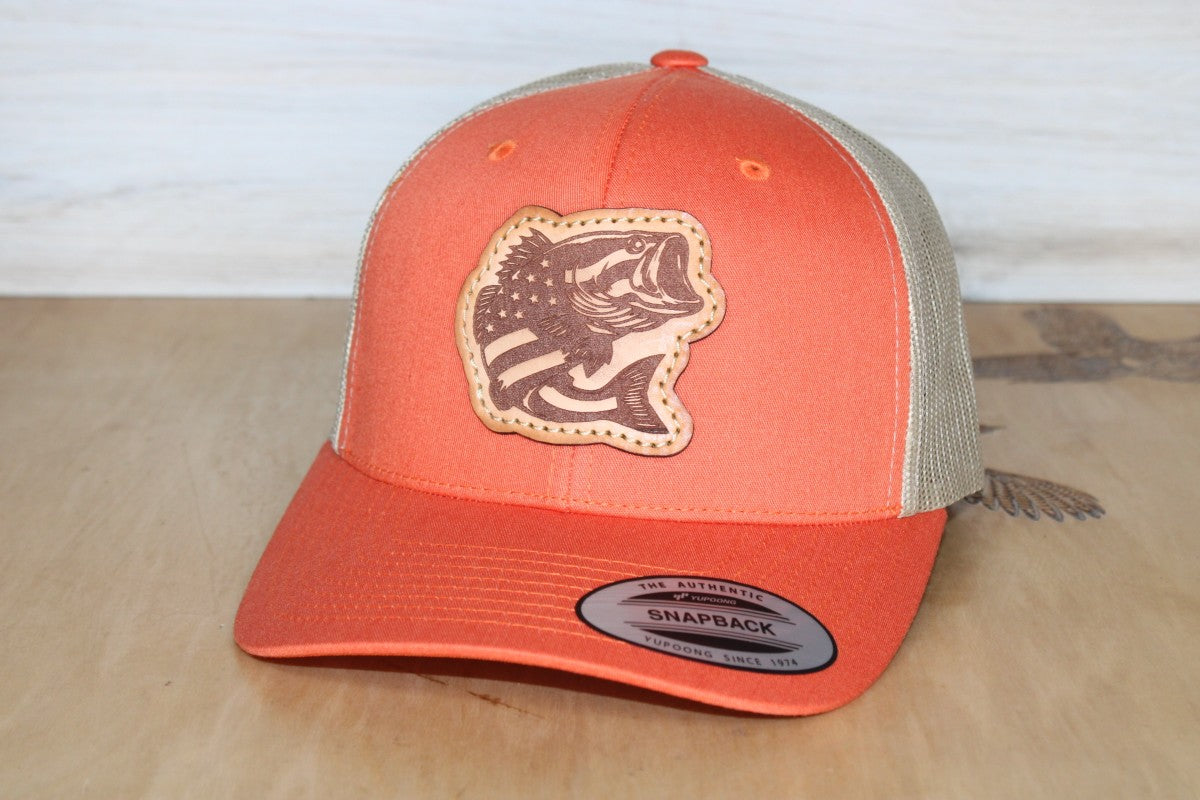 Orange and beige cap with a fish logo on a wooden surface