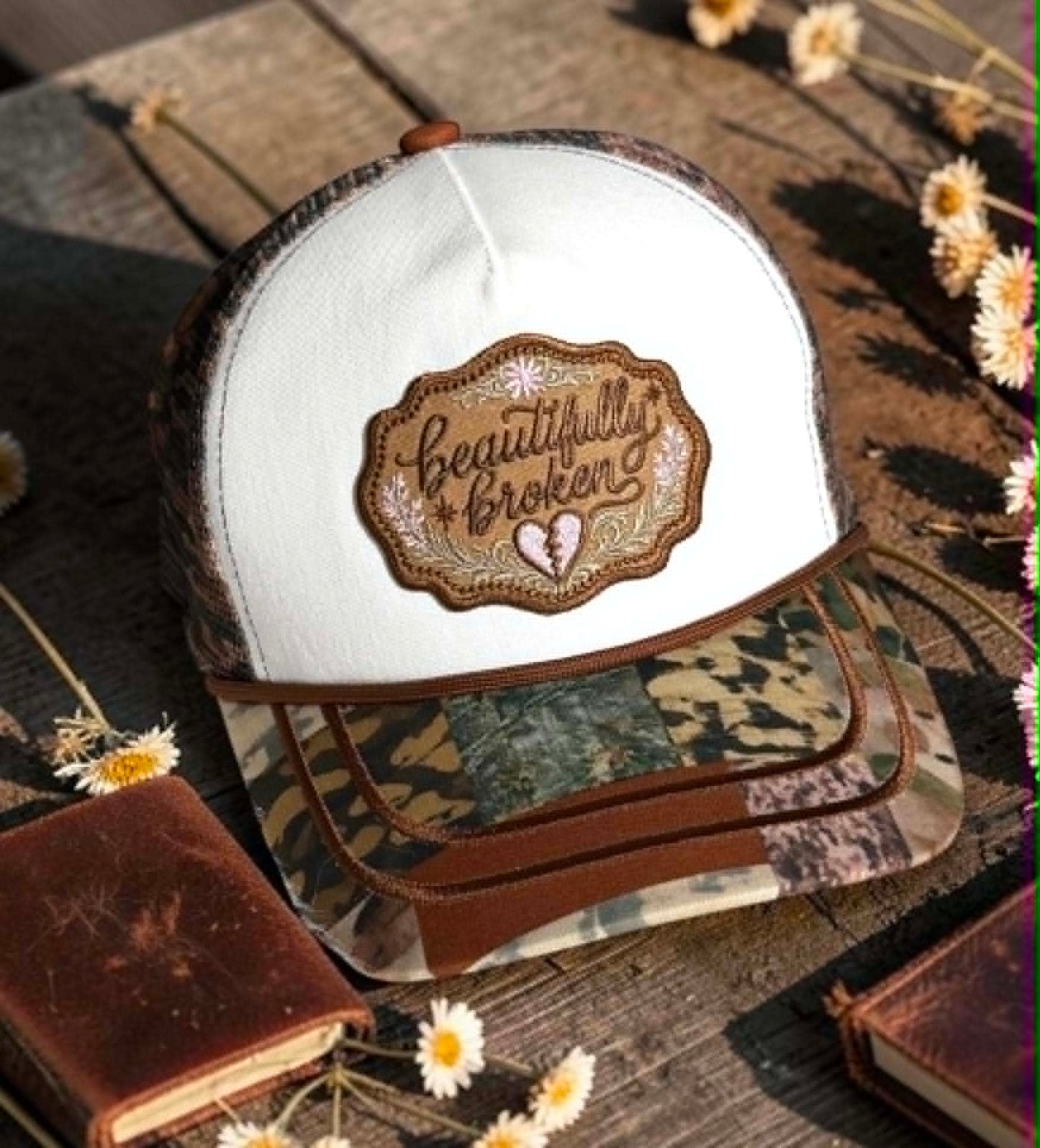 Cap with 'Beautifully Broken' patch on a rustic background