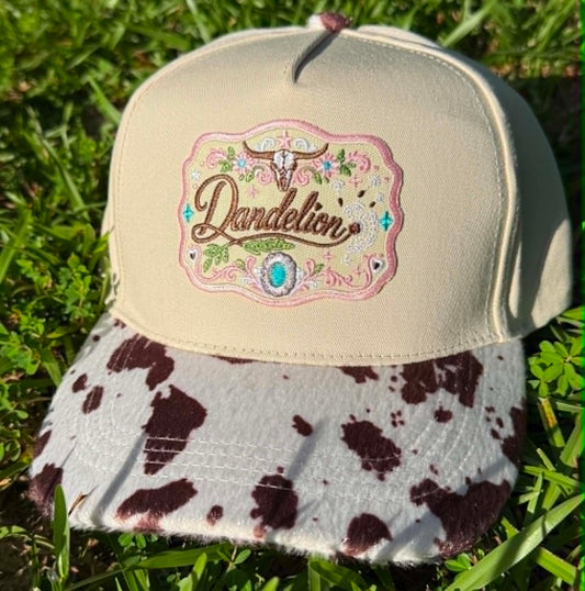 Beige cap with cow print brim and 'Dandelion' logo on grass