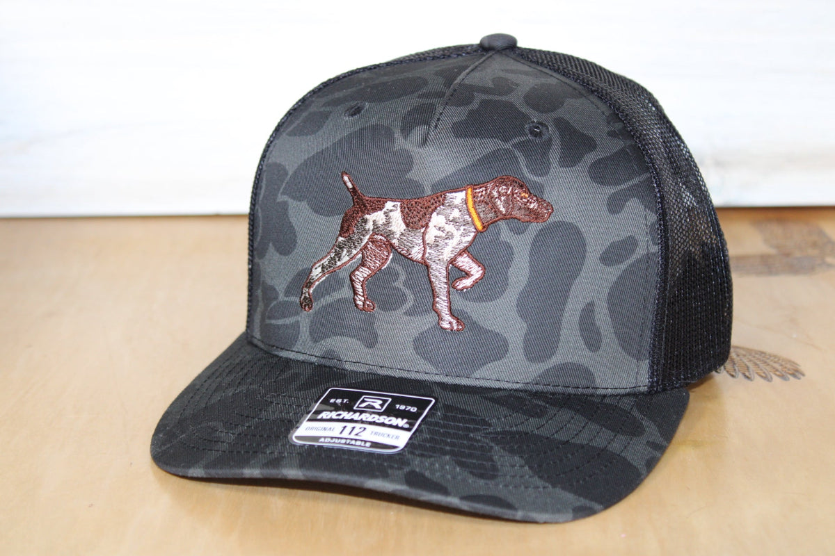 Camouflage cap with a dog design on a wooden surface
