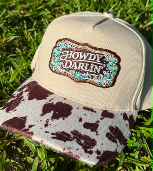 Cap with 'Howdy Darlin' logo on a grass background