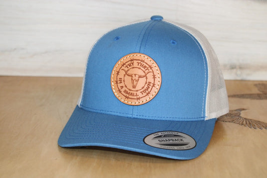 Blue and white cap with a try that in a small town leather patch