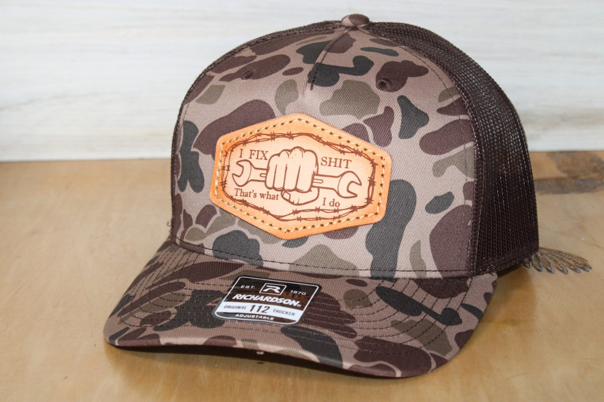Camouflage trucker hat with leather patch on a wooden surface