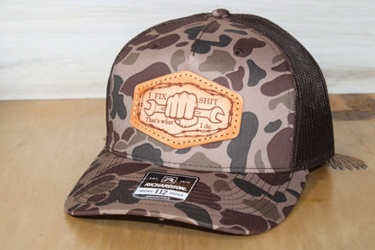 Camouflage trucker hat with leather patch on a wooden surface