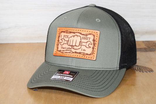 Green and black cap with a blue collar leather patch I Fix Shit