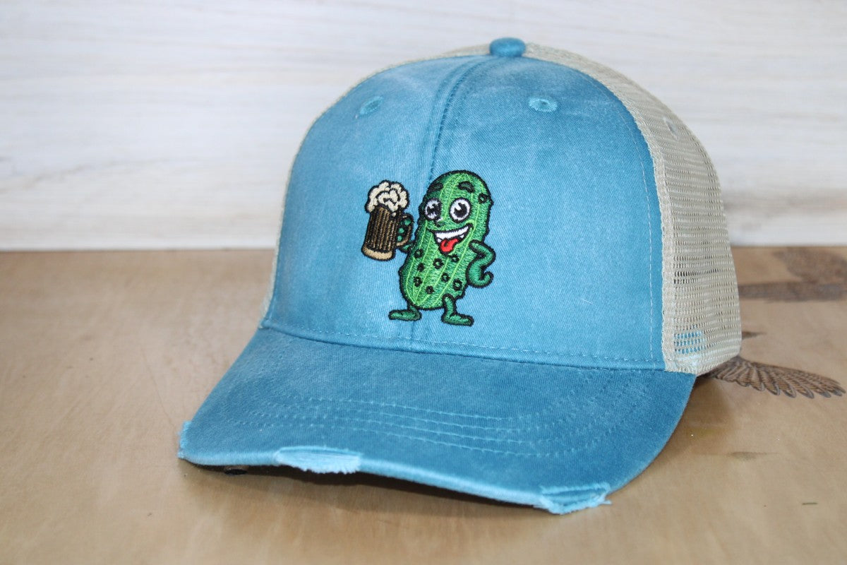 Blue cap with a pickle holding a beer on a wooden surface